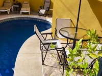 частный бассейн с шезлонгами и столом для отдыхающих в доме