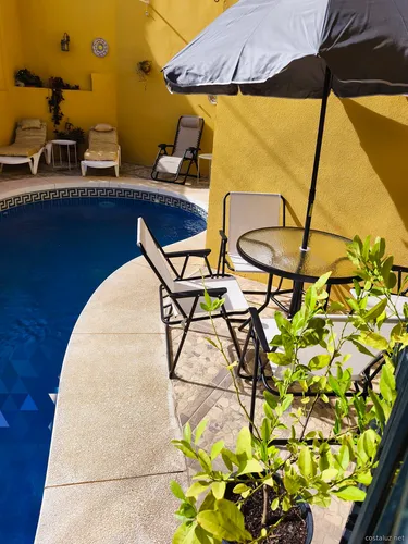 частный бассейн с шезлонгами и столом для отдыхающих в доме